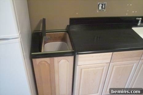 Discreet Waste Solutions 6 The fully integrated custom trash can cabinet with its doors closed, appearing as a regular part of the kitchen wardrobe, showcasing its hidden design and clean aesthetic.