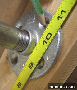 MEASURING SOME STANDS. Close-up of the end flanges being attached to the 2x4 lumber base, demonstrating the assembly of the stand's foundation.