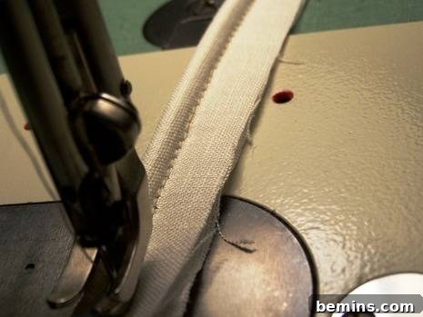 Sewing machine in action, creating a continuous fabric-covered welt cord with precise stitching