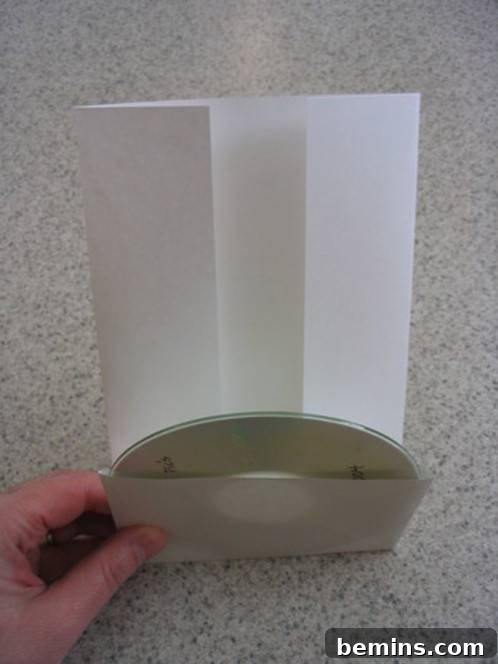 The CD is being inserted into the front pocket.