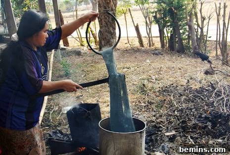 Crafting Silk The Essential 6 Steps 4 A person dipping naturally dyed silk threads into a silver pot in an outdoor setting.