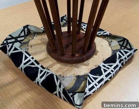 Continuing to staple the fabric around the stool