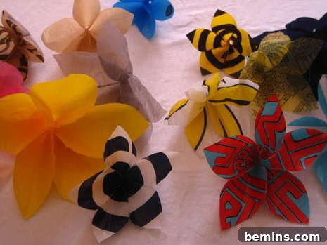 Colorful flower decorations sit on a white surface, showcasing the beautiful results of upcycling plastic bags.