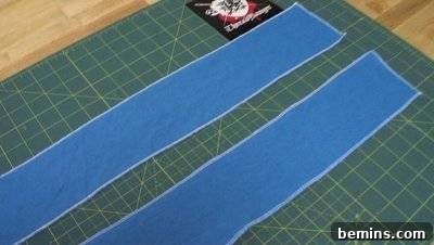 Two strips of blue cloth that is laid out on a green board. DIY Backpack Straps.