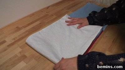 A person laying out white fabric. Folding Fabric.