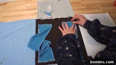 A person is working with blue material on a black surface. Attaching Backpack Straps.