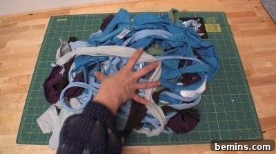 A person is grabbing at fabric scraps on a green grid. Making a Pillow.