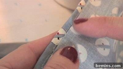 Woman showing blind hem stitch on fabric edge with hands.