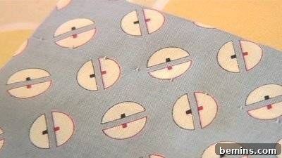 A blind hem along one edge of a gray fabric with a repeating half-circle geometric pattern.