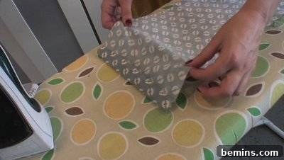 A woman is steaming a blue and white cloth to get it smooth.