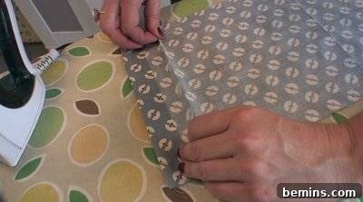 A person works with blue and white material on another green and yellow material.