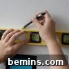 Penciling in the internal grid lines for a Mondrian-inspired wall design using a spirit level, showing careful planning before tape application.