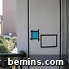 Applying and trimming black electrical tape lines with a craft knife to create a precise Mondrian-inspired geometric pattern on a wall.