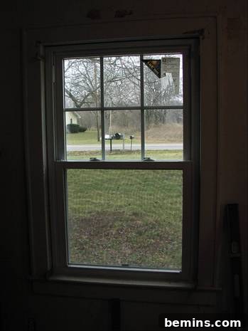 A newly installed modern wood window overlooking a lush grassy area with a mailbox, symbolizing a successful home renovation.