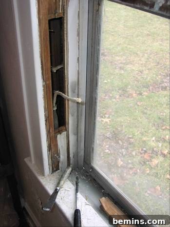 A dirty window pane with tools sitting on its sill, showcasing the before state of a historic home's windows during renovation.