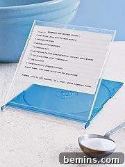 Text is written on a piece of paper in a CD case near a spoon on a white surface.