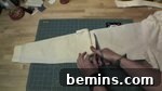 A person cuts a white shirt with scissors, as it lays on a green crafting mat.