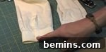 Someone is pointing to a closure on a piece of clothing that is on a sewing mat.