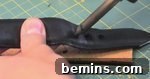 A man poking a pencil into a piece of leather material.