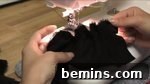 Two hands grabbing black fabric on a table, preparing to sew the ruffles.