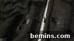 A silver zipper between black material, securing the closure of the skirt.