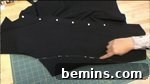 A hand working on black fabric, preparing to reattach the sleeves with modifications.