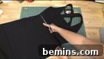 A girl cutting a black dress with scissors to make a witch skirt.