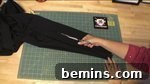 An arm of a jacket is being cut up the center with a knife, creating the slit for the sleeve.