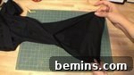 Person stretching fabric out on a sewing table, preparing to hem the sleeves.