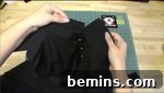 A person is using black material to make a shirt, attaching the sleeves to the armholes.