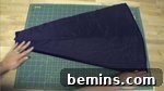 A person sewing together a black costume, attaching the contrasting triangle to the sleeve slit.