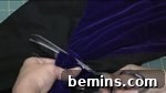 A person cuts blue fabric with metal scissors, using a different contrasting fabric for the front of the sleeve.