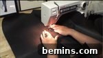 A series of leather flaps being sewed in a machine, potentially used as embellishments on the hat.