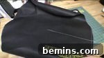 A black piece of fabric or vinyl is being measured with a craft ruler, cutting the fabric for the hat's covering.