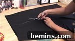 A person cutting a piece of black cloth to create ruffles for a witch skirt.