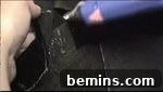 A person uses a crafting tool on black fabric, folding the excess fabric into the hat for a clean finish.
