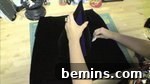 A person working on black fabric, cutting out the fabric for the hat's brim.