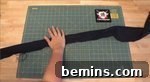A long, thin piece of black cloth is on a crafting mat, ready to be used as a waistband.