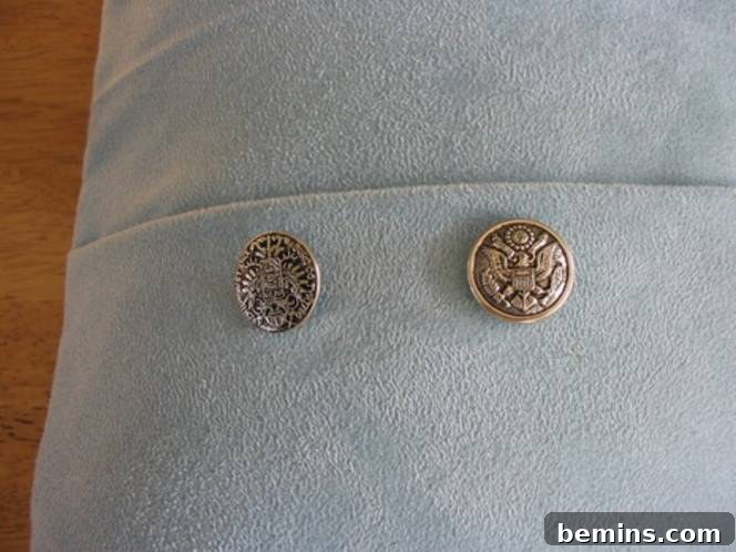 Two buttons are on a light blue fabric.