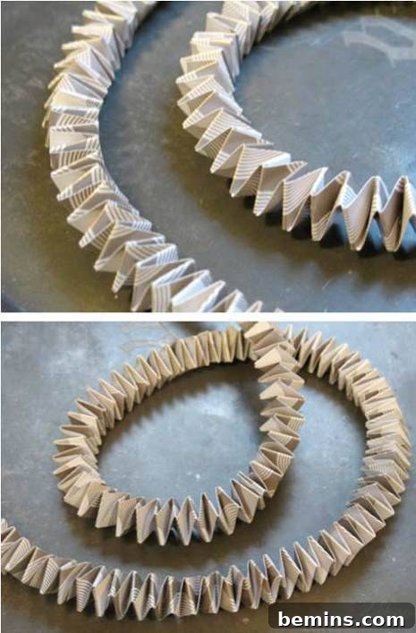 Long strips of beige paper with images or writing are folded to form an accordion rope, demonstrating the folded paper technique.