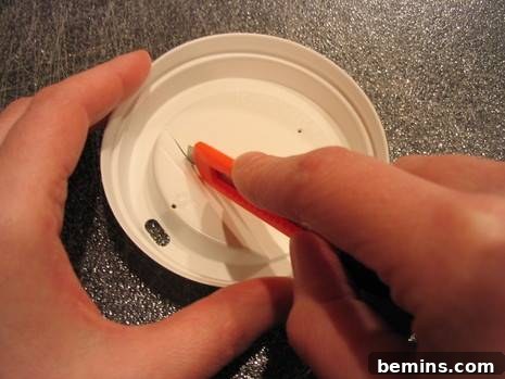 Crafty Coffee: DIY Tissue Dispenser 4 A person is cutting the white lid of a cup on a counter.