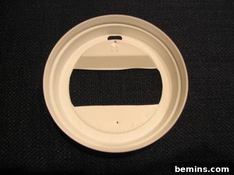 A white lid sitting on a black surface.