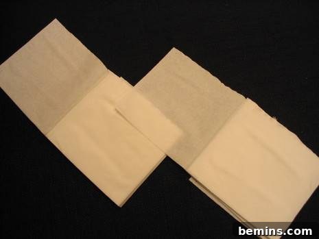 Two brown sheets of paper towel are sitting on a black surface.