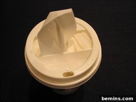 Paper towels are coming out the lid of a cup.