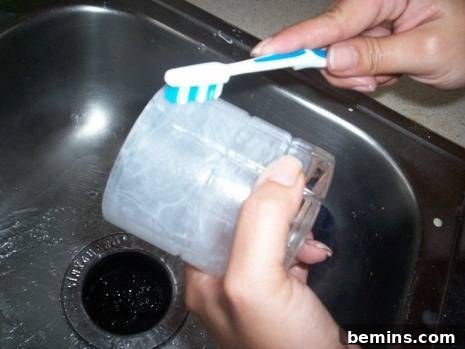 Cleaning Cloudy Glassware: Restoring Shine and Clarity 3 Applying white toothpaste to a drinking glass with a toothbrush