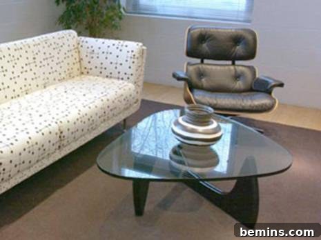 Triangular glass coffee table next to couch and chair in a living room.