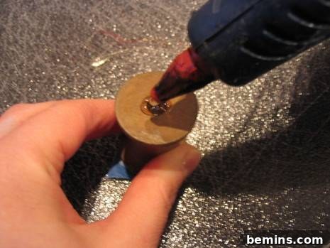 Applying hot glue to a wooden spool
