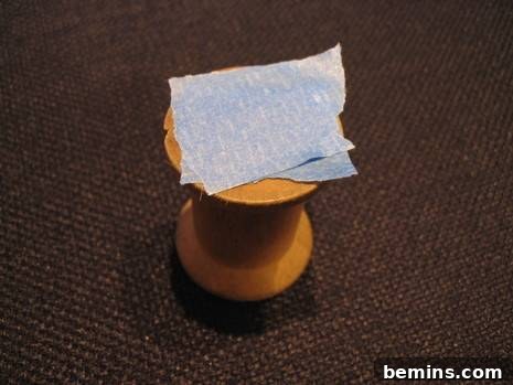 A wooden spool with tape over the bottom hole