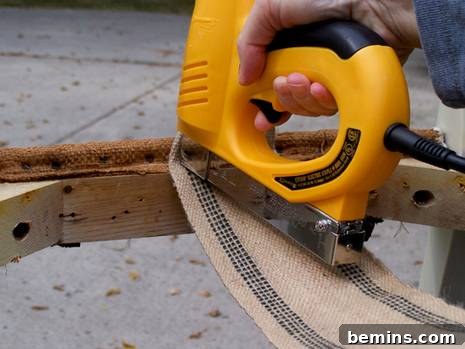 Stapling the first webbing strip to the chair frame