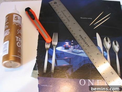 A collection of essential crafting tools and materials neatly arranged on a wooden table, including colorful magazine pages, a bottle of craft glue, toothpicks, a ruler, and a utility knife, all ready for a paper bead making project.